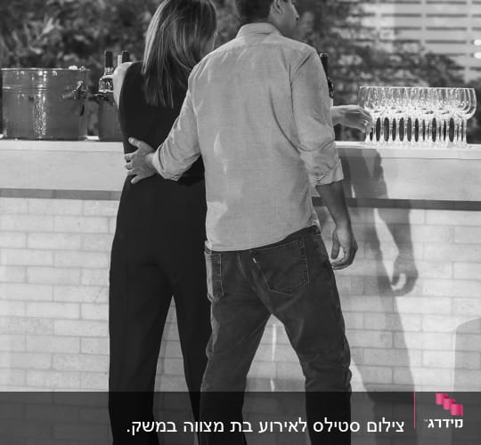 צילום בשחור-לבן של זוג עומד ליד בר משקאות באירוע